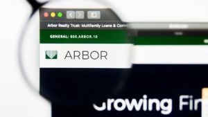 the Arbor Realty Trust (ABR) logo on a web browser, magnified by a magnifying glass