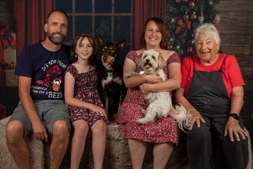 three adults, a child and two dogs pose for a santa photo