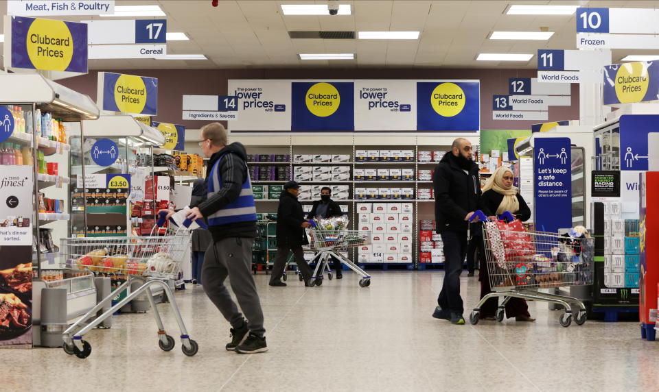 Shoppers walk next to the clubcard price branding inside a branch of a Tesco Extra Supermarket in London, Britain, February 10, 2022. Picture taken February 10, 2022. REUTERS/Paul Childs