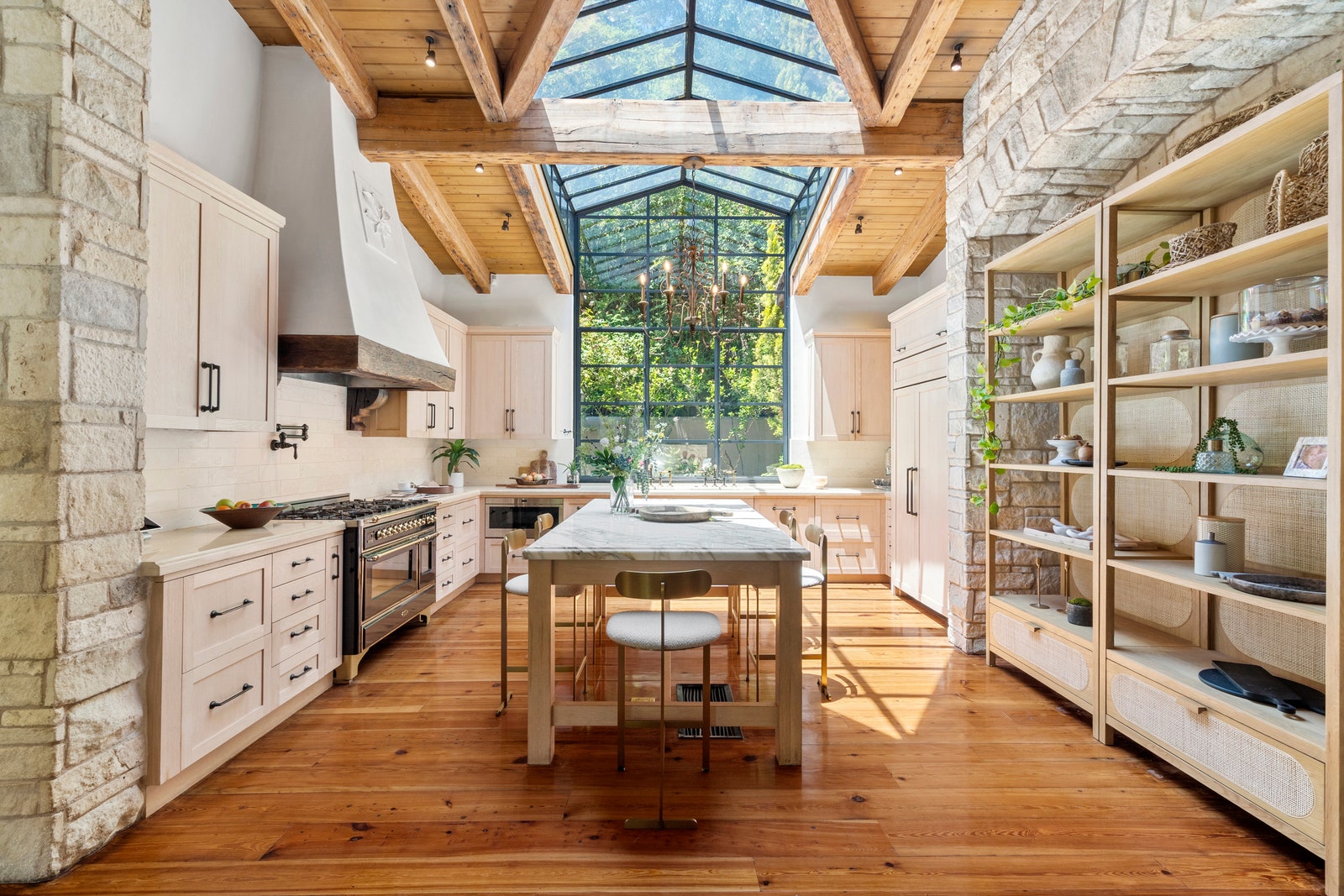Kitchen in Jennifer Lopezs former home with large central island tented skylights overhead white cabinetry rustic gray...