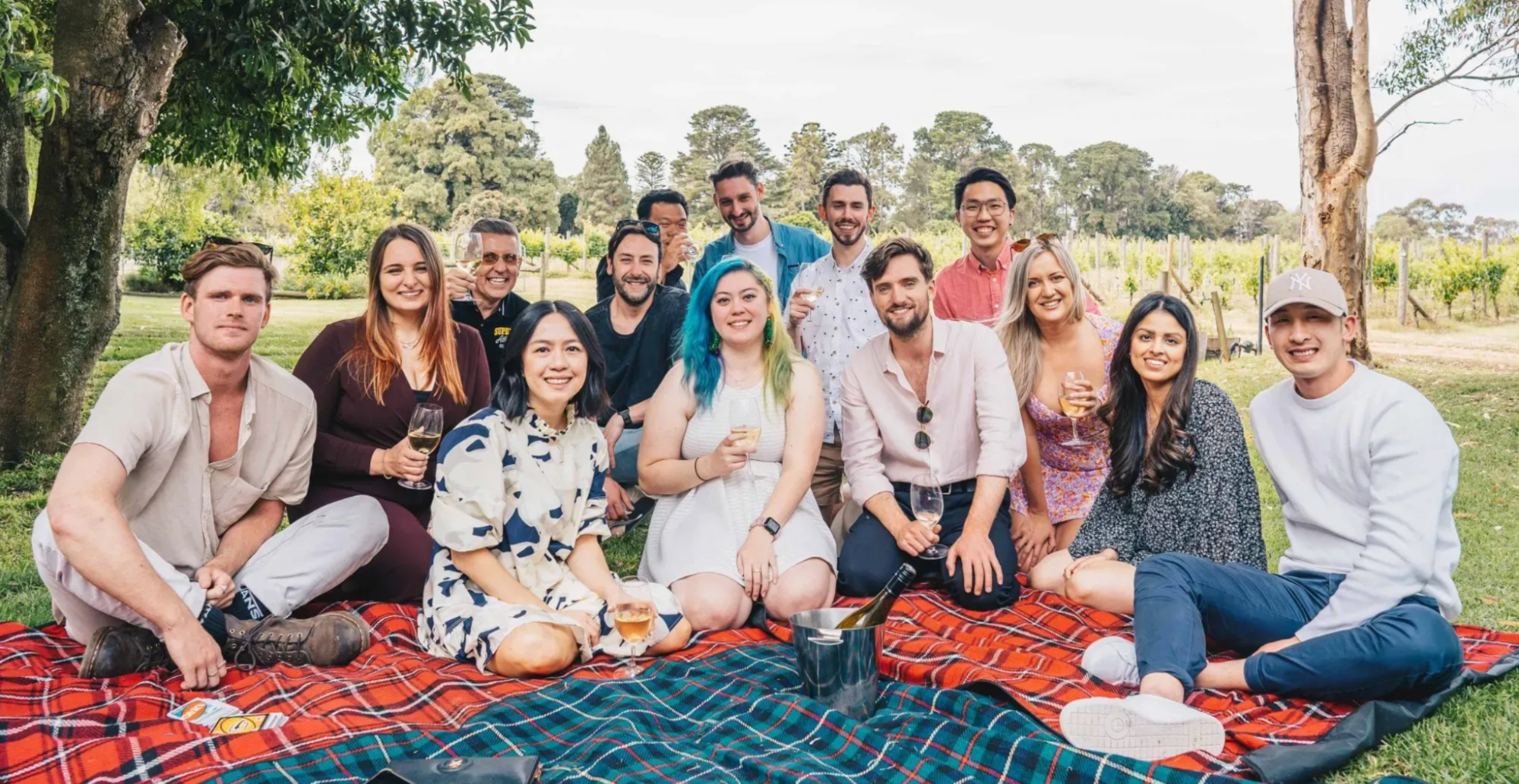 The Exo Digital team poses for a photo, sitting on picnic rugs at a vineyard.