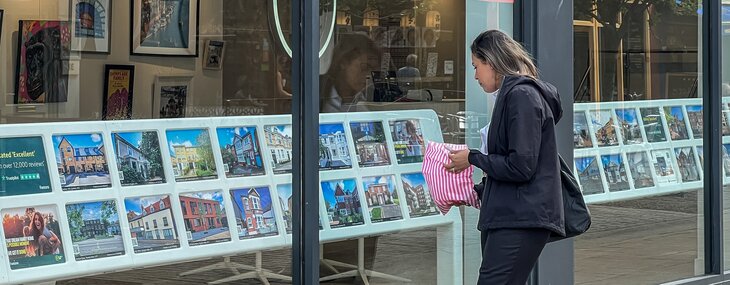 A woman is pictured looking into the window of an upmarket lettings agent.