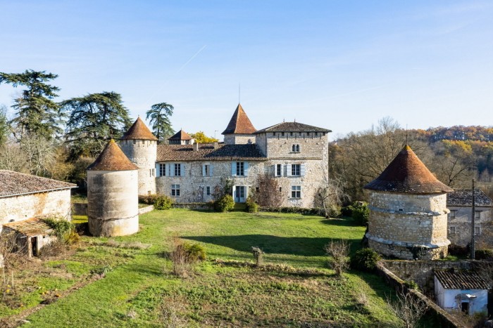 A medieval château with multiple red-tiled towers surrounded by countryside