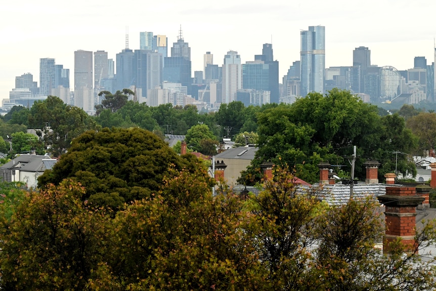 The high-rise towers in Melbourne CBD in the distance, with green trees and houses in the foreground.