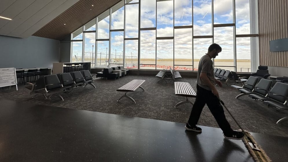 Garden City Regional Airport maintenance worker Jacob Ochampaugh sweeps the floors of the new departure gate. The airport terminal was revamped this year, as airport officials expect increased ridership. (AJ Dome/Kansas Reflector)